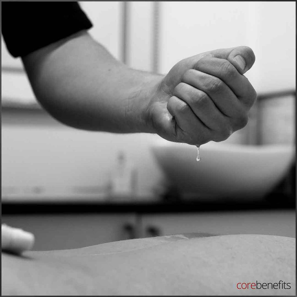 A close-up in black and white of a clenched fist with a droplet of massage oil, symbolizing the precision and care in massage treatments at Core Benefits Toowoomba, offering services like sports, remedial, lomi lomi, and full body massage tailored for men's wellness.