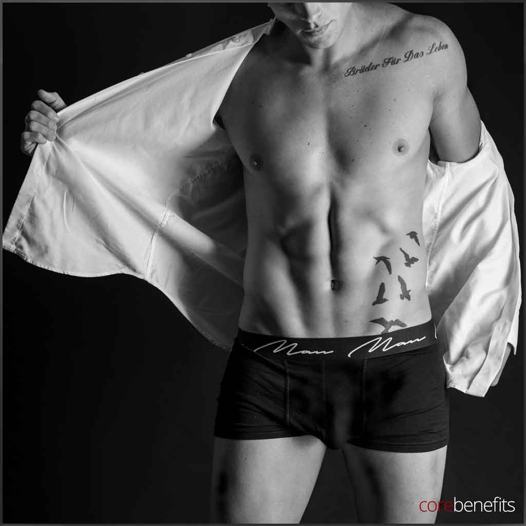 This striking black and white image features a fit male model, capturing the results of body contouring services available in Toowoomba. He stands confidently with his shirt open, showcasing a sculpted torso that reflects the benefits of treatments like cool sculpting, weight loss programs, and fat removal techniques. The photo embodies men's health and the fight against stubborn fat, illustrating the aesthetic goals attainable through dedicated care at Core Benefits Toowoomba.