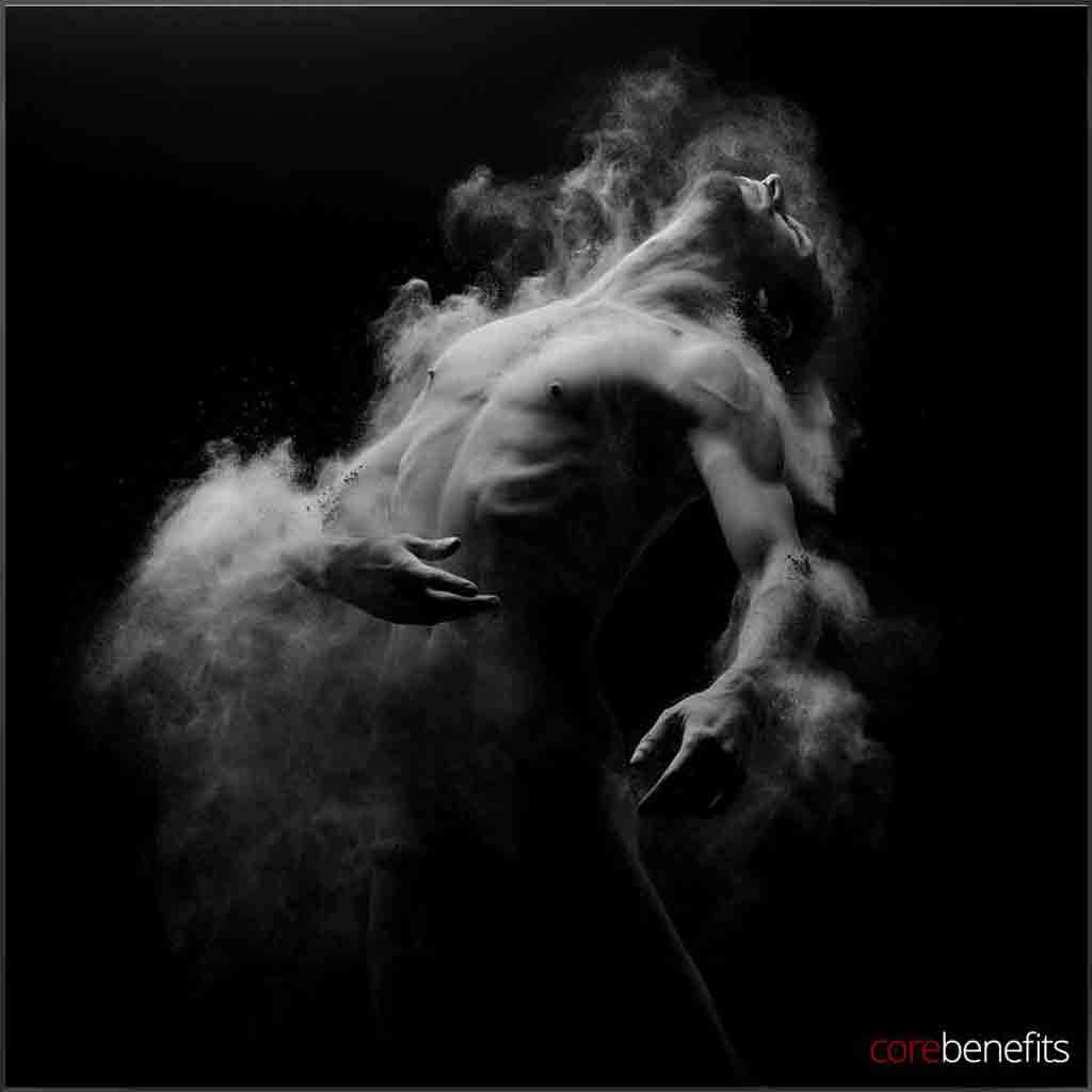 Artistic black and white image of a man with dust swirling around him, symbolizing skin rejuvenation from an exfoliation massage at Core Benefits Toowoomba. Experience the transformation and renewal of 'Bare to Bold: Effortless Confidence' with a full body scrub massage in Toowoomba.