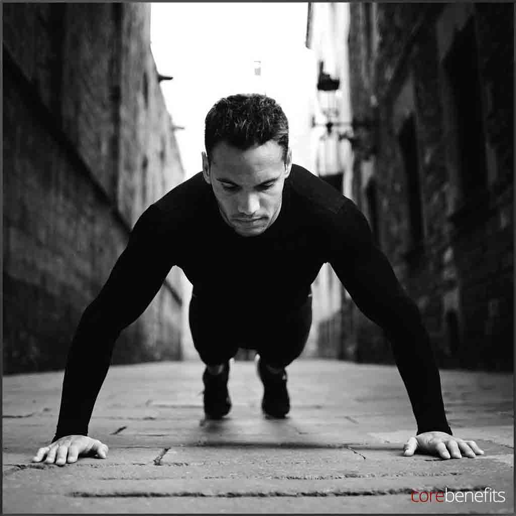 Intense monochrome image of a man in a push-up position on an alleyway's cobblestone path, representing strength and resilience. Core Benefits Toowoomba offers sports massages to enhance men's athletic performance and recovery, ensuring 'Bare to Bold: Effortless Confidence Begins Here'.