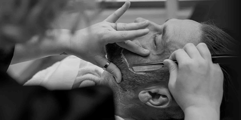 Barber Toowoomba. In a classic barbershop moment, a skilled barber in Toowoomba is captured carefully shaving a customer with precision. This image encapsulates the traditional barber experience, highlighting quality men's haircuts and grooming services available near you.